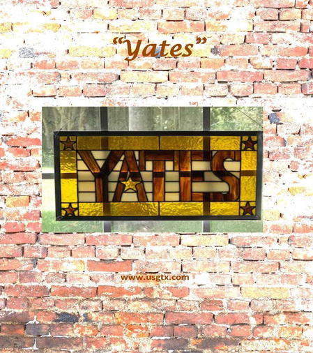 Amber stained glass sign with the word Yates in block letters and a gold star.